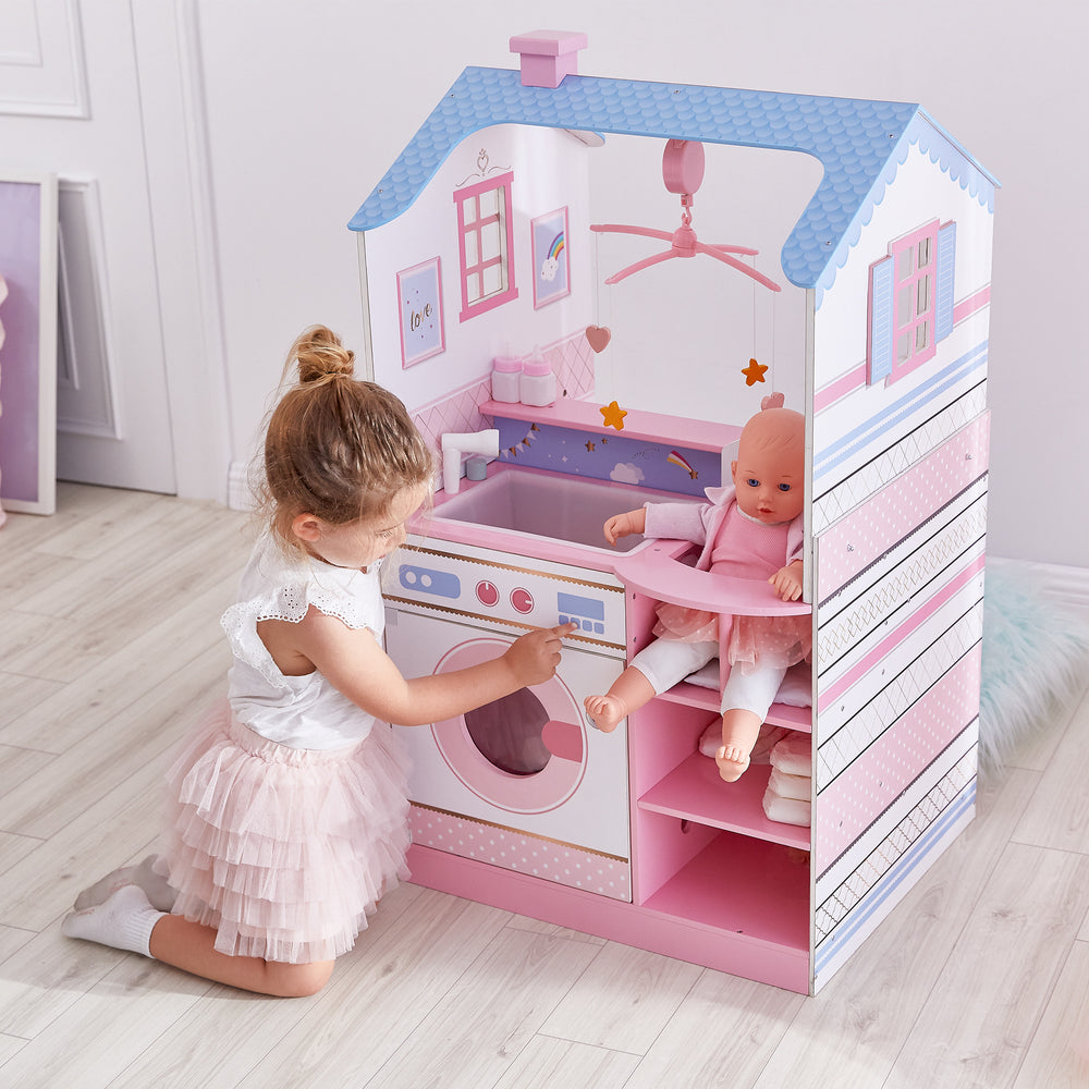 A little girl pretends to start the pretend dishwasher while her baby doll sits in the high chair.