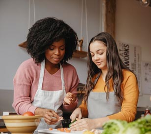 two girls cooking and chopping vegetables