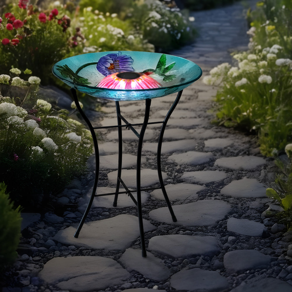 birdbath on a pathway in a garden at night, LED lights aglow