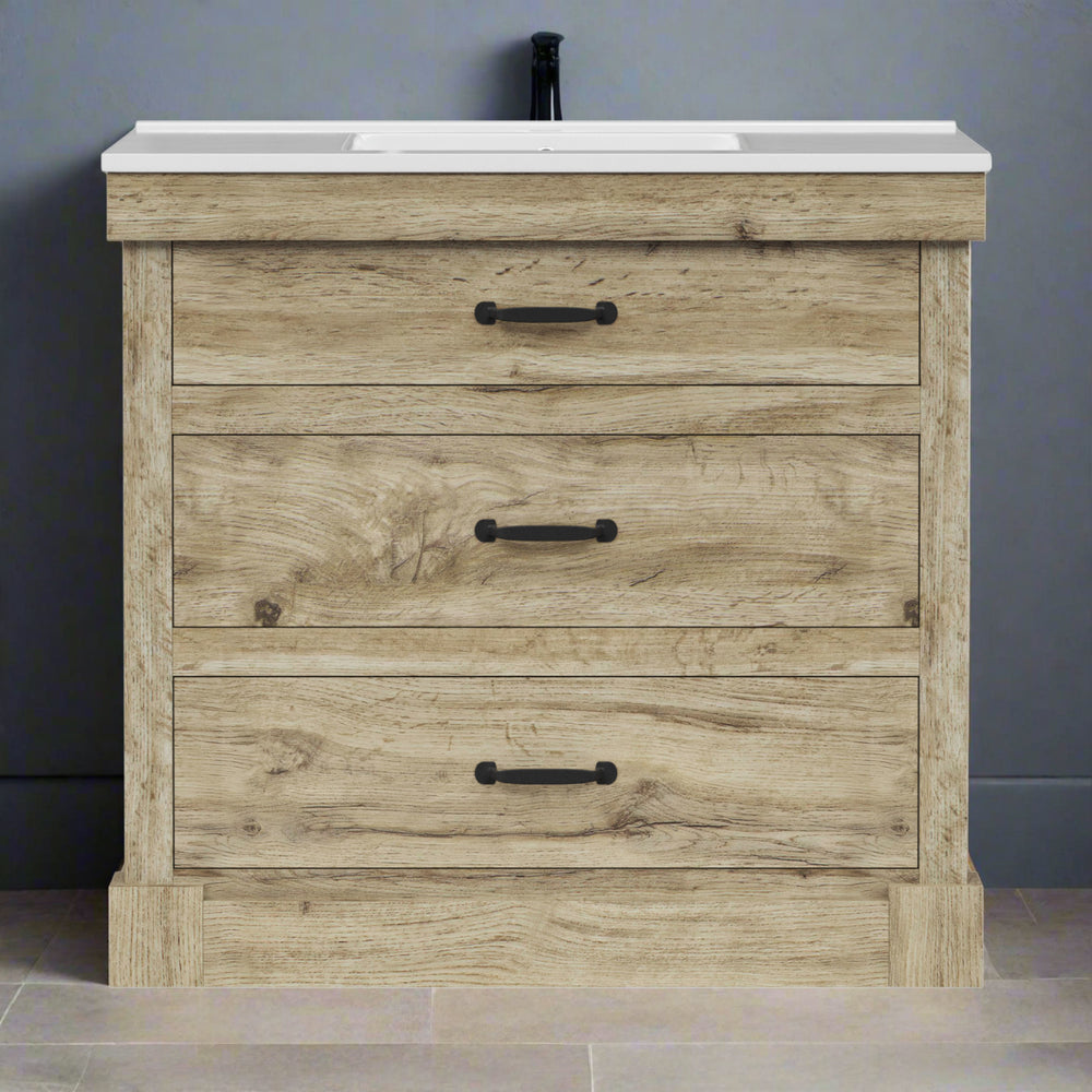 Light oak finished sink vanity with a white ceramic sink against a gray wall.