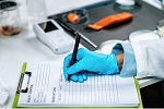 Inspector filling out a quality control form in a laboratory