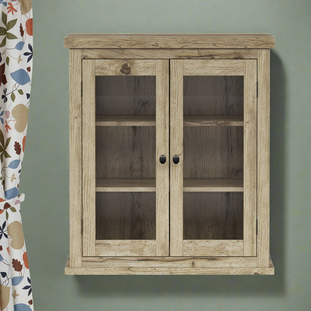 Light oak wall cabinet on a sage green wall with a colorful curtain.