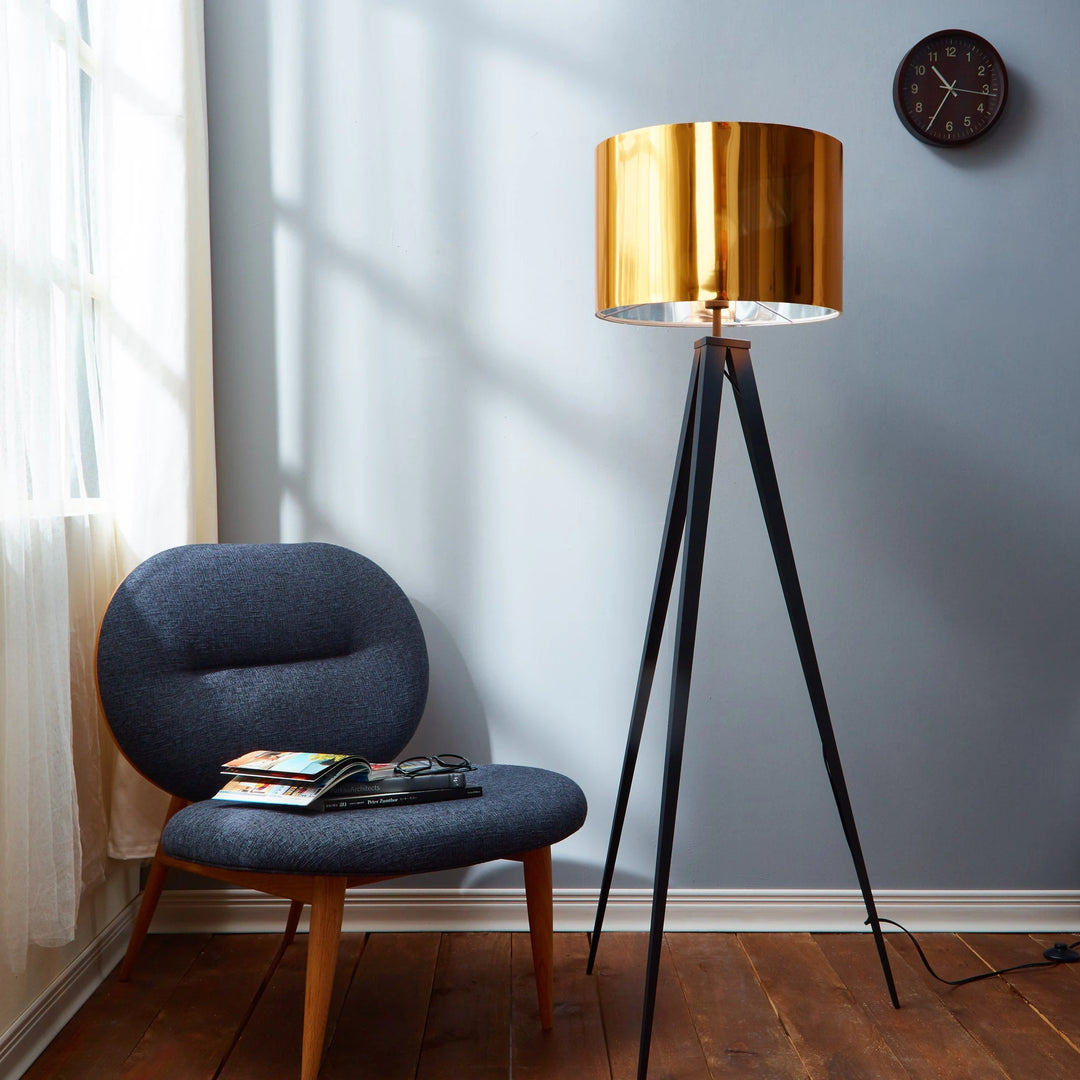 a large drum shade tripod lamp stands next to a grey chair