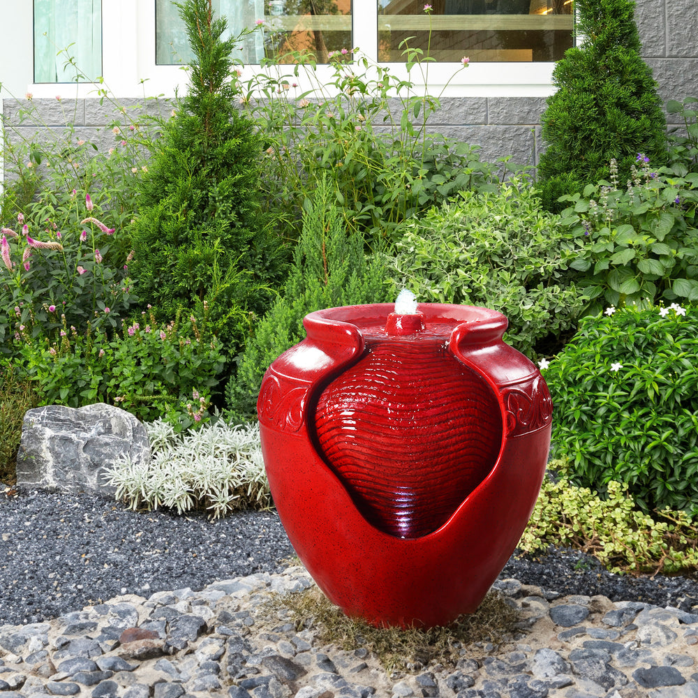 A red vase-shaped water fountain in a garden