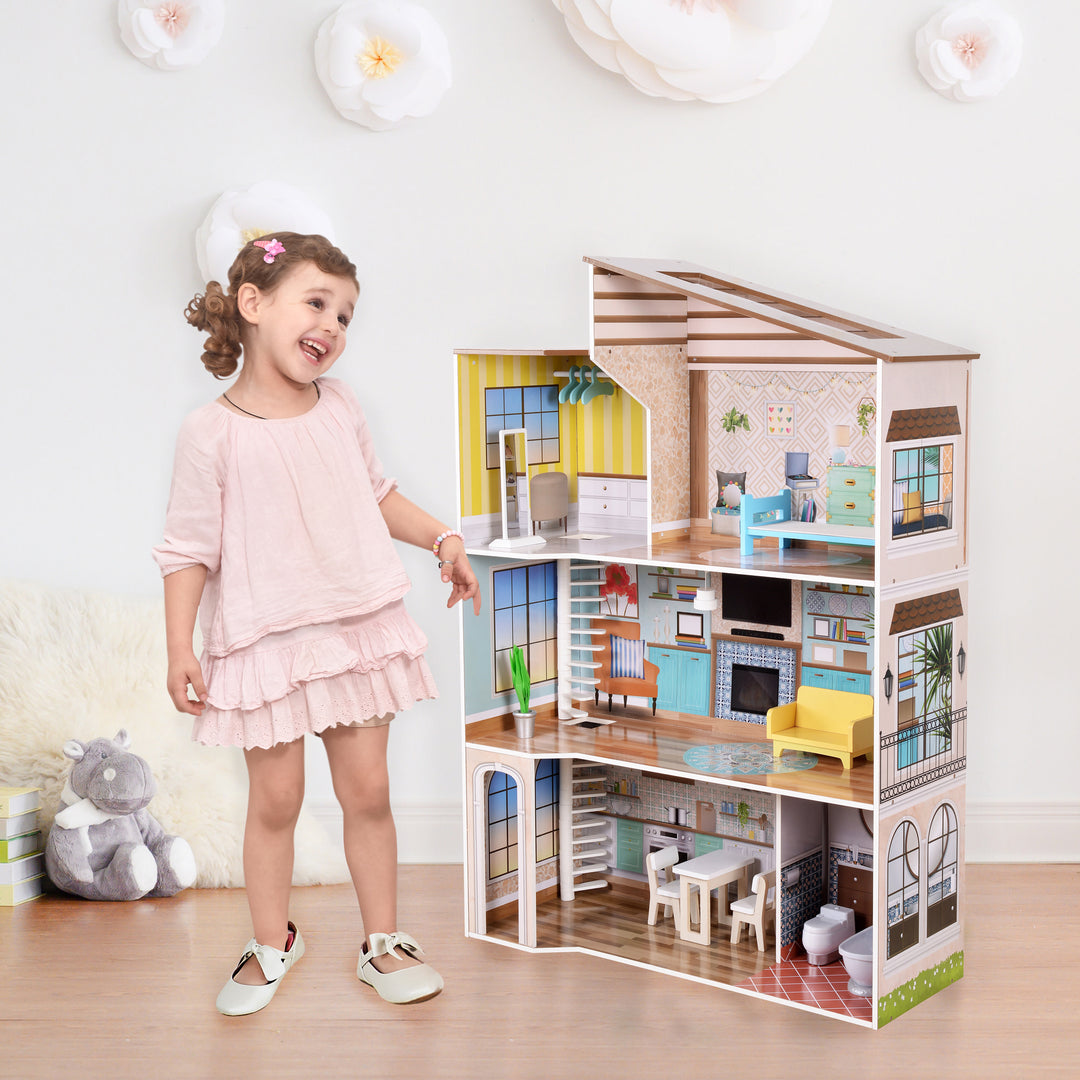 A little girl in a pink dress standing next to a three-story dollhouse.