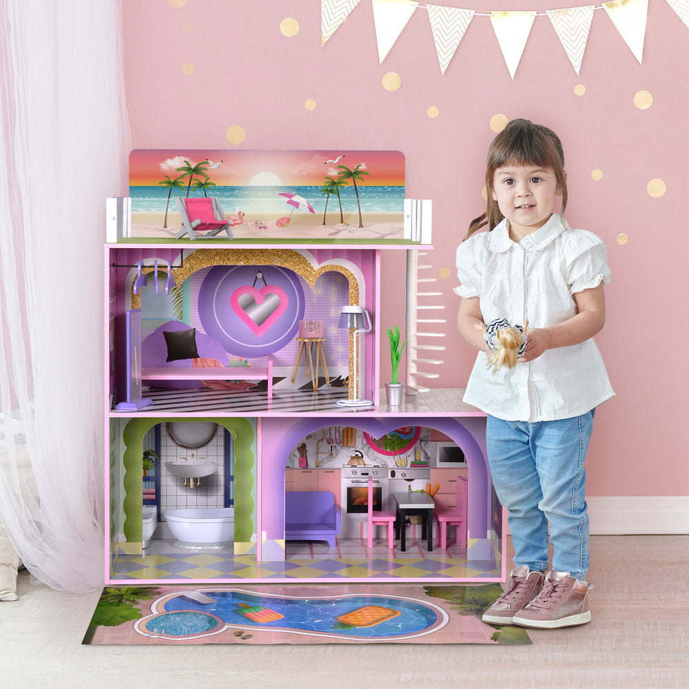 A little girl holding a blond doll next to a two-story dollhouse.