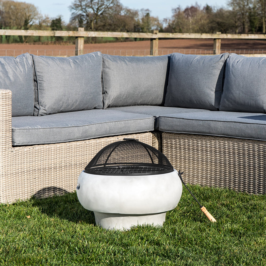 a fire pit column sits in front of patio sofa on the grass