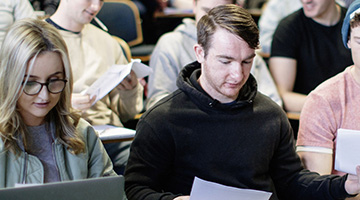 Image for Students passing notes at a lecture