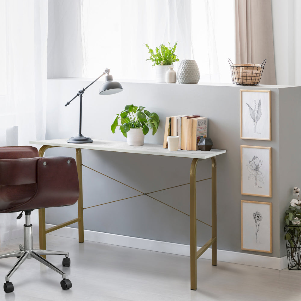 Teamson Home's 40" Computer Desk with a Faux White Marble desktop/Brass frame in a room with a chair and a plant.